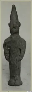 Terracotta figurine of a standing figure with a tall pointed head and arms held close to the sides.