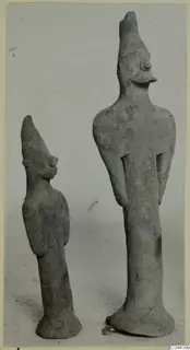 Two terracotta figurines of standing figures with tall pointed headdresses, photographed side by side against a plain grey background.