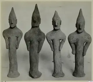 Four terracotta figurines from Ayia Irini standing in a row, each with a tall pointed head and a flared base
