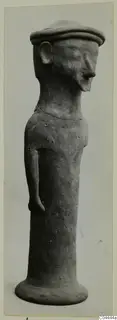 Terracotta figurine of a standing figure with a flat cap, one arm at its side and a flared base