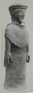 Standing terracotta figure with a flat cap and long pointed nose, shown in side view against a pale backdrop