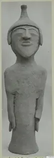 Terracotta figurine of a standing figure with a tall conical headdress, arms at the sides and a flared base