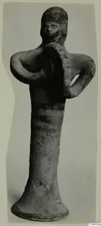 Terracotta figurine of a standing figure holding a round, ridged disc against its chest, with dark painted bands on the body