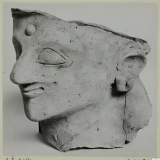 Terracotta head fragment from Ayia Irini, shown in profile facing left, with the top edge broken away