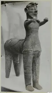 Terracotta figure of a standing human figure joined to a four-legged animal body, shown against a plain backdrop