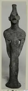 Terracotta figurine of a standing figure with a tall narrow neck, flat ears and arms held close to the body, from Ayia Irini