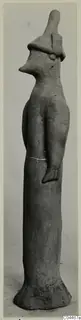 Terracotta figurine of a standing figure with a tall hat-like cap and a pointed, beak-like face