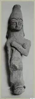 Terracotta figurine with a tall cylindrical headdress and one arm folded across the chest, photographed against a grey backdrop.