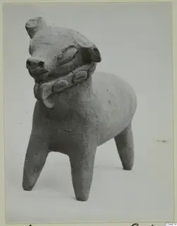 Terracotta figurine of a standing four-legged animal with a band around its neck, photographed against a pale background