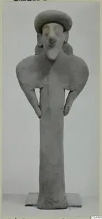 Grey terracotta figurine of a standing figure with a broad cap-like head and hands resting on the hips