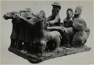 Terracotta model of a chariot drawn by three horses, with a driver holding the reins and two figures standing at the back.