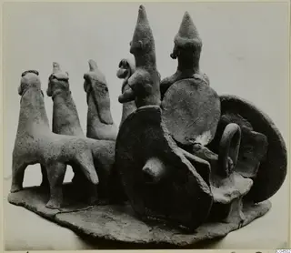 Terracotta group of small figures with animals and disc-shaped forms on an oval base