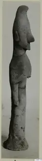 Terracotta figurine of a standing figure in profile, with a tall head, long projecting nose and a flat base