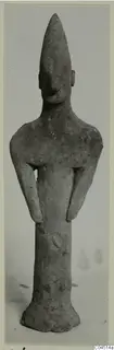 Terracotta figurine of a standing human figure with a tall pointed head and arms bent at the sides.
