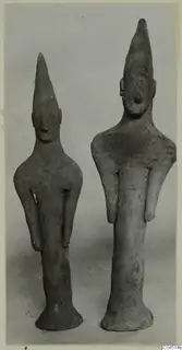 Two terracotta figurines with tall pointed heads and flared bases, standing side by side