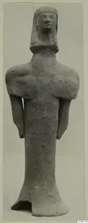 Terracotta standing figurine with arms at its sides and a broken base, photographed frontally against a plain grey background.