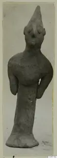 Terracotta figurine from Ayia Irini with a tall conical head and bent arms, standing on a flared base