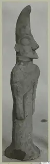 Terracotta figurine standing upright, with a tall tapering headdress and a large round eye in relief.