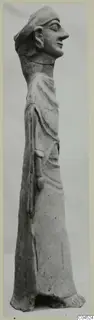 Terracotta standing figure in profile facing right, wearing a cap and a draped garment, with one arm bent at the waist.