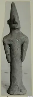 Standing terracotta figurine with a tall pointed head, narrow body and flared base, from Ayia Irini