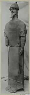 Terracotta statue of a standing bearded male figure in a long robe, shown full length