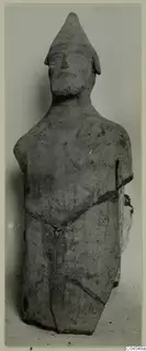 Terracotta figure of a standing human figure with a tall conical cap, shown from the front against a plain background