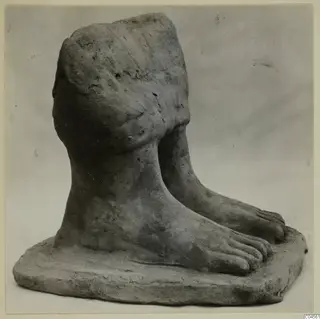 Terracotta fragment showing two bare feet with toes on a thick flat base, with a rounded modelled upper part