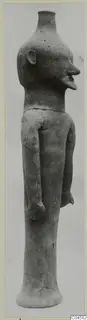 Terracotta standing figure with long arms and a flared base, shown against a plain grey background
