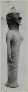 Terracotta figure of a standing figure with a pointed conical cap and long neck, shown in profile.