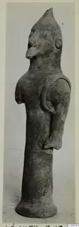 Terracotta figurine with a pointed head, large nose and a tall cylindrical lower part