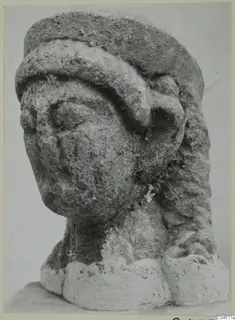 Limestone head from a statue from Arsos, with a worn face and a thick band across the brow.