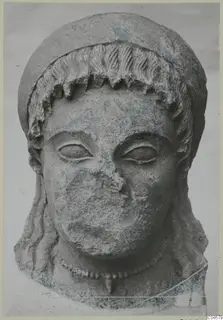 Limestone head of a figure from Arsos, with a hair band, a plain face and a beaded necklace.