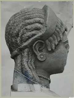 Limestone sculpture of a female head in profile, with elaborate curled hair and a large ear spiral, from Arsos.