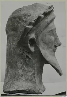 Terracotta head in profile from Mersinaki, with a long pointed nose and a band of leaf-like shapes across the top