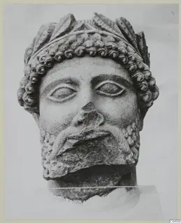 Limestone head of a bearded figure from Arsos, with curled hair, a broken nose and a chipped beard