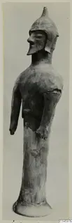 Terracotta figure of a helmeted standing figure on a tall cylindrical base, shown in profile against a grey backdrop.