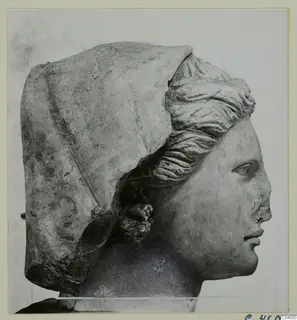 Carved stone head in right profile, with a veil over the head and a chipped nose.