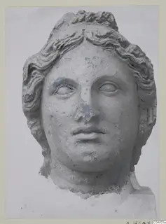 Stone statue head from Arsos, a female face with wavy hair swept back, nose and surface worn.