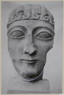 Limestone head sculpture with a band of spiral scrolls across the forehead, on a square block base.