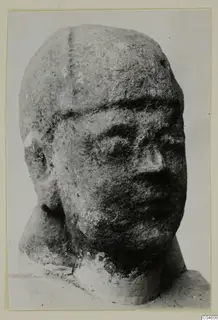 Limestone head with a broad face and weathered surface, photographed in three-quarter view