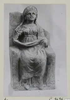 Seated stone statue of a woman from Arsos, shown against a grey backdrop.