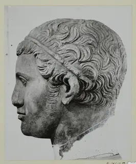 Stone head from a statue at Arsos, shown in left profile, with short wavy hair and a band across it.