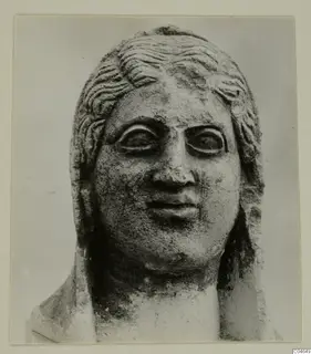 Carved stone head and upper shoulders of a statue from Arsos, shown frontally with wavy hair and large eyes