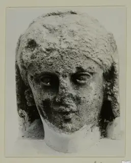 Stone head of a statue from Arsos, shown face on with worn features.