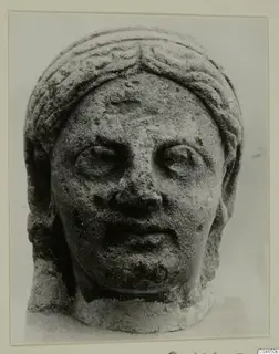 Stone head from Arsos, face and headdress carved in limestone, viewed from the front.