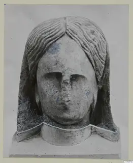 Stone head sculpture from Arsos, front view, with wavy hair parted at the centre and a broken nose