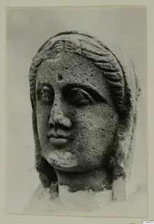 Stone statue head from Arsos, shown close up with wavy hair bands and a broken neck.