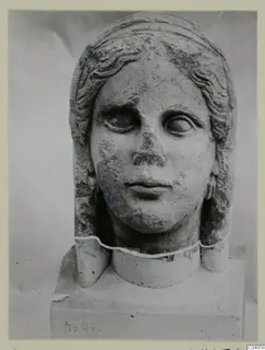 Stone statue head and neck from Arsos, with wavy hair framing the face and a block base