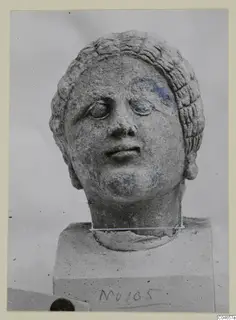 Stone statue head from Arsos, a female head with hair in wavy rows, on a square block base