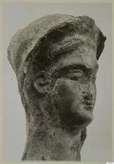 Head of a terracotta figure from Mersinaki, with a close-fitting cap and a worn, pitted surface